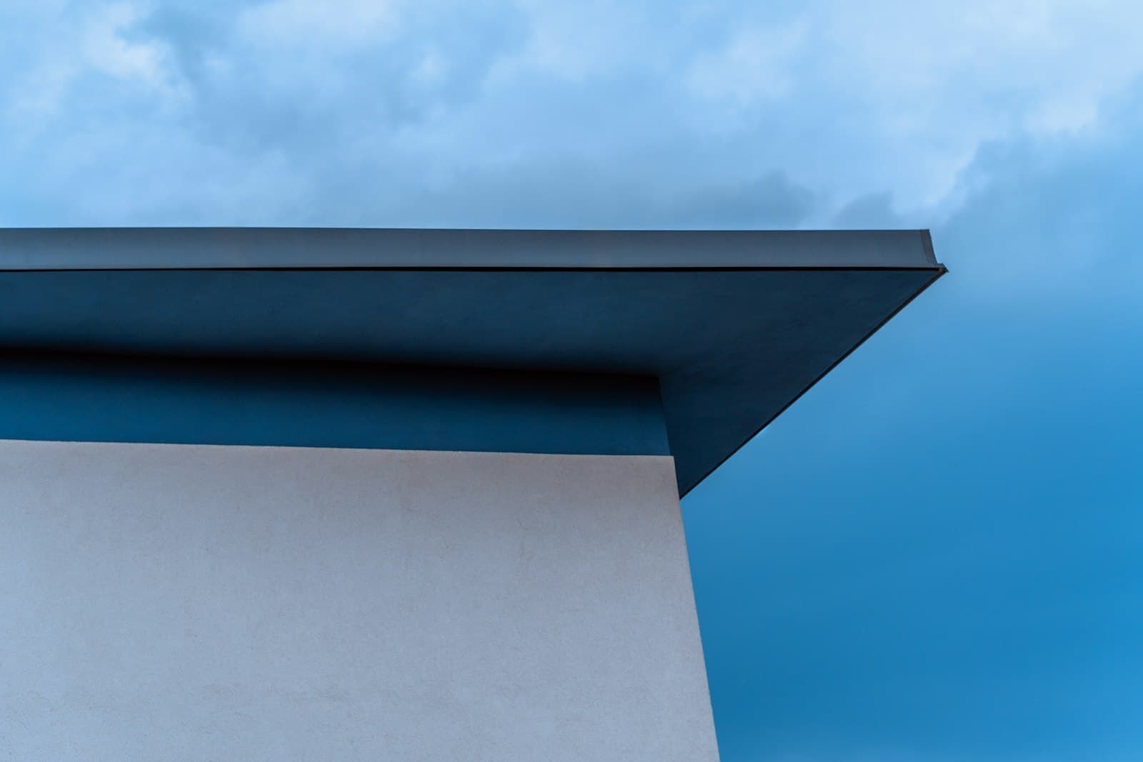 Modern flat roof edge silhouetted against a blue sky.